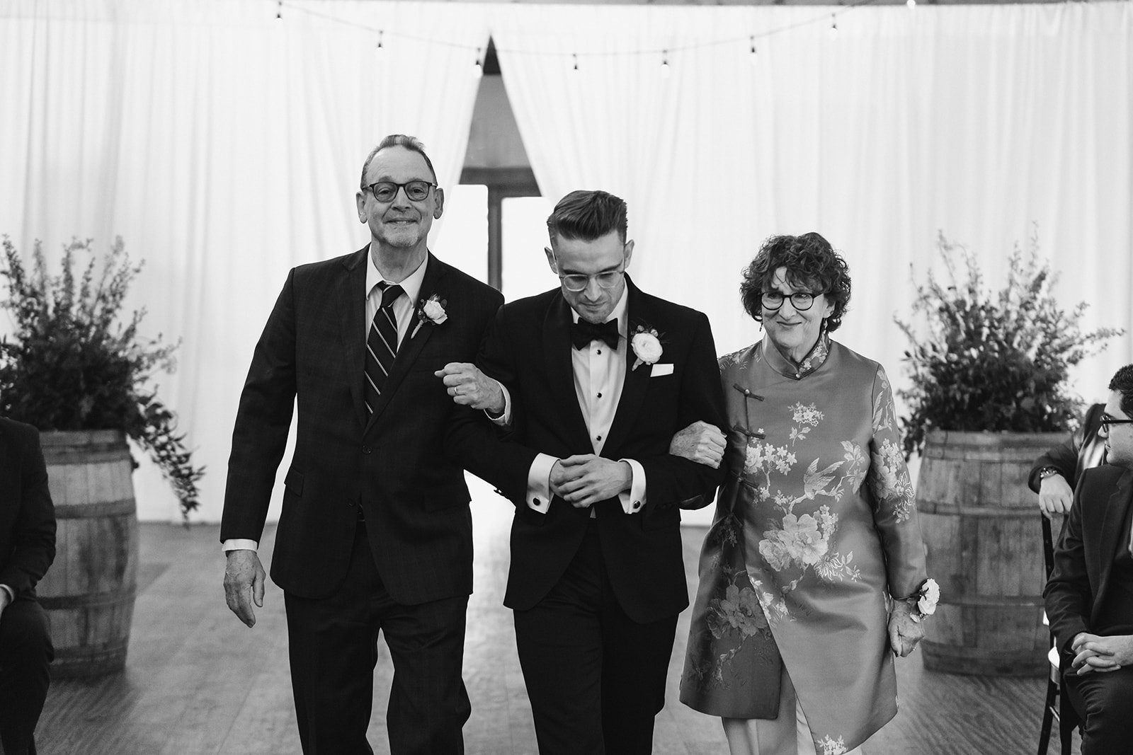 groom is walked down the aisle by mother and father