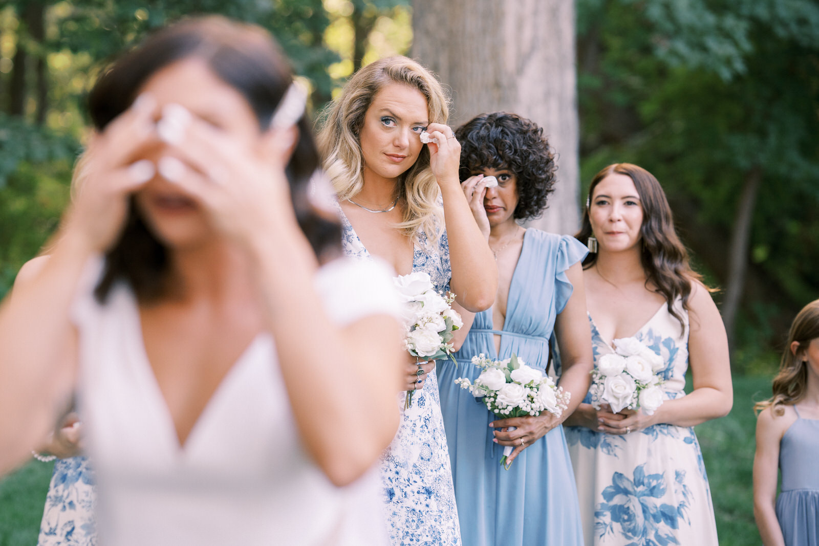 bridesmaids in blue wipes tears from eyes